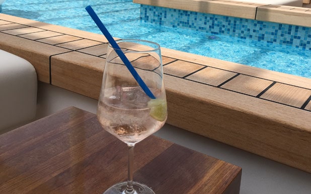 Cocktail-Glas mit Strohhalm und Limette am Hotelpool